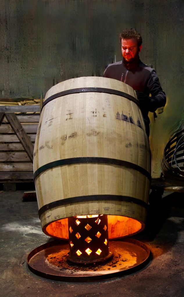 Un employé en train de chauffer une barrique dans l'atelier de la tonnellerie